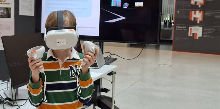 Ein Junge sieht sich in der Umgebung um, während er ein VR-Headset trägt und in beiden Händen Controller hält. Ein Junge sieht sich in der Umgebung um, während er ein VR-Headset trägt und in beiden Händen Controller hält.